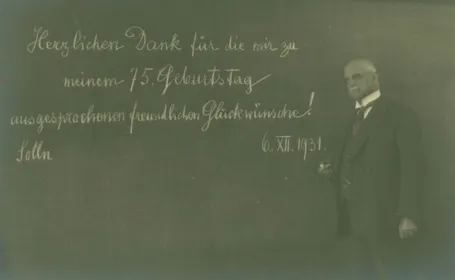 s/w Foto von Walther von Dyck vor einer Tafel mit dem Schriftzug: "Herzlichen Dank für die mir zu meinem 75. Geburtstag ausgesprochenen freundlichen Glückwünsche!"